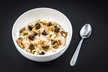 Oatmeal recipe with nuts, plums, cinnamon and sugar prepared for breakfast with black background
