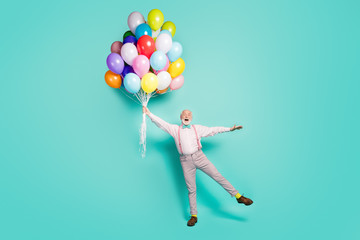 Full size photo excited amazed grey white bearded old man hold balloons flying wind in sky impressed scream wow omg wear pink pants trousers footwear bowtie isolated turquoise color background