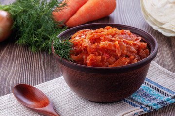 Braised cabbage with tomatoes on an old wooden background in rustic style