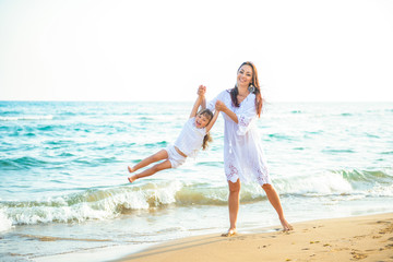 Fototapeta na wymiar Happy family mom and little daughter play and fool around the coast on sea beach at resort