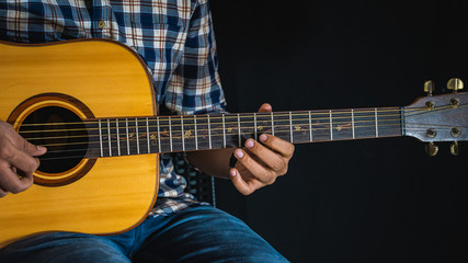 A guitarist playing a note on an acoustic guitar