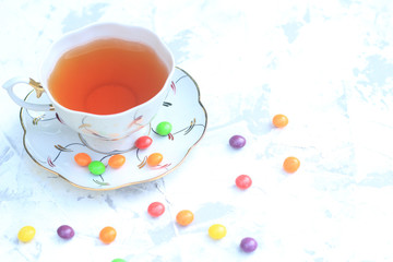 Cup of tea with sweets on a light background.