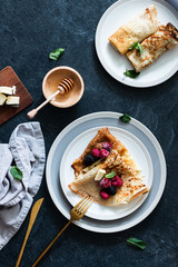 crepes with fresh berries and sweet sauce on dark table