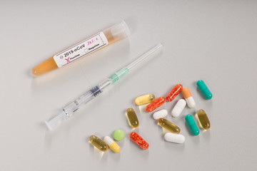 a virus test tube with positive marker and a syringe and pills for treatment