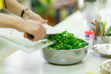 Cook in the kitchen cuts greens close up