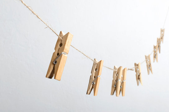 Closeup of wooden laundry pegs on the rustic rope aginst white background