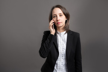 Portrait of wonderful young business woman talking on cellphone, poseing on isolated gray background