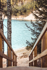 Wooden staircase with trees and a lake in background. Sandy beach.  Moody calm tones. Located in...