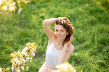 Naklejka na ściany i meble Young attractive girl walks in spring green park enjoying flowering nature