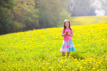 Naklejka na ściany i meble Kids play. Child in dandelion field. Summer flower