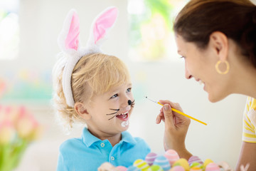 Mother and kids, family coloring Easter eggs.
