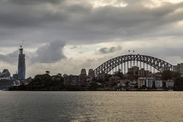 Sydney in Australia, the skyline with the Harbour Bridge during a cloudy but warm day in summer.