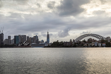 Fototapeta na wymiar Sydney in Australia, the skyline with the Opera house and the Harbour Bridge during a cloudy but warm day.