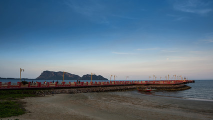 Fototapeta na wymiar The red bridge and the people who exercise Walk to see the view at Prachuap Bay in the evening time in Thailand.