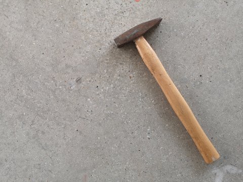 Steel hammer with a wooden handle is placed on the surface of the stone