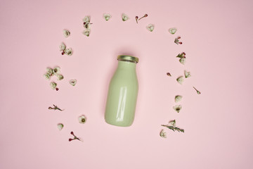 green bottle of smoothy on pink background with small flowers
