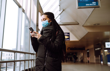 Girl in protective sterile medical mask on her face with a phone in  quarantine city. Woman using the phone to search for news. The concept of preventing the spread of the epidemic. 
