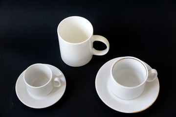 Different white cups for coffee on a black background.