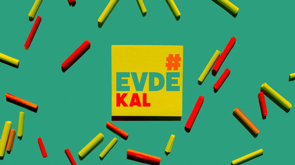 evde kal yellow post it paper and green background 