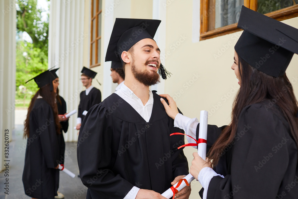 Wall mural Female graduates with diplomas in their hands hugging