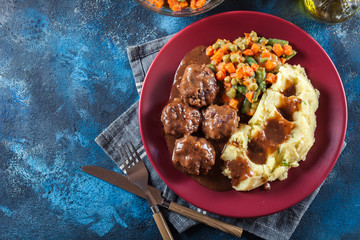 Roasted meatballs in dark sauce with mashed potatoes
