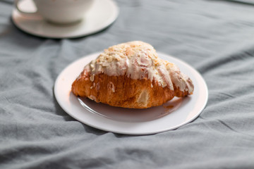 Aromatic coffee and fresh baked croissant on the bed. Breakfast in bed.