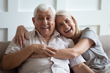 Happy older wife and husband hugging and laughing together, having fun, smiling mature father and...