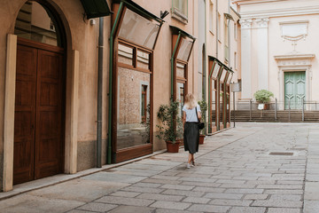 A beautiful woman with blond hair walks through the streets of the city. Girl enjoy holidays in Europe. Beautiful historical architecture. Italian weekend. Travel to Turin, Italy. Adventure lifestyle