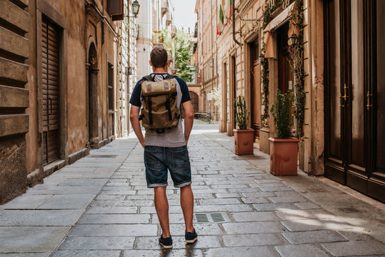 Fototapeta A man with a backpack walks through the streets of the city. Tourist enjoy holidays in Europe. Beautiful old historical architecture. Italian weekend. Travel to Turin, Italy. Adventure lifestyle