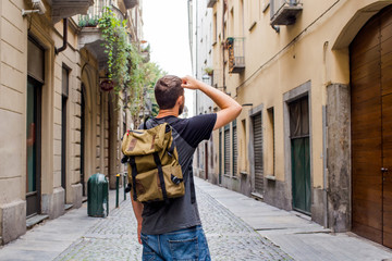 A man with a backpack walks through the streets of the city. Tourist enjoy holidays in Europe. Beautiful old historical architecture. Italian weekend. Travel to Turin, Italy. Adventure lifestyle
