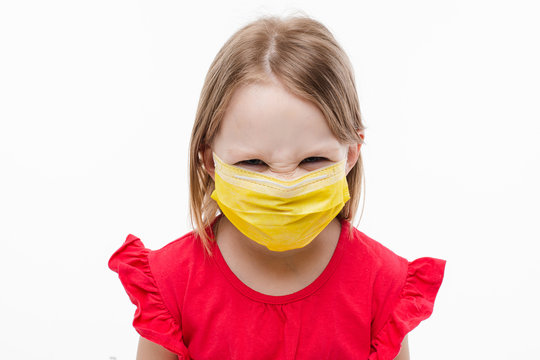 Picture Of Little Beautiful Caucasian Girl With Long Fair Hair In Red Dress With Yellow Medical Mask On Her Face Is Angry