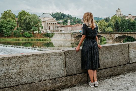 Fototapeta A beautiful woman with blond hair walks through the streets of the city. Girl enjoy holidays in Europe. Beautiful historical architecture. Italian weekend. Travel to Turin, Italy. Adventure lifestyle