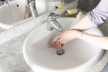 Woman washing hand in bathroom interior. Washing hands  for  prevention against any virus concept.