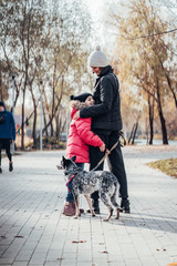 Happy mother and her daughter walk with dog in autumn park