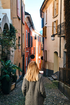 Fototapeta A beautiful woman with blond hair walks through the streets of the city. Girl enjoy holidays in Europe. Beautiful historical architecture. Switzerland weekend. Travel to Locarno, Swiss. Adventure life