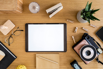 Stylish flat lay business composition on the wooden desk with mock up tablet, cacti, notes, photo camera and office supplies in modern concept of home office.