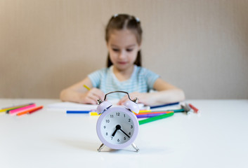 Girl studies at home. Girl draws with colored pencils and sits at a white table