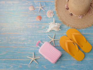 Beach accessories on blue wooden plank, summer holiday on the beach concept, hat, seashell, starfish, laggage and slippers