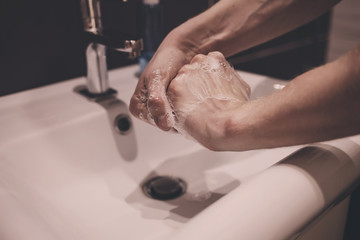 Man washing hands with soap under the faucet with water. Concept hygiene and cleanliness