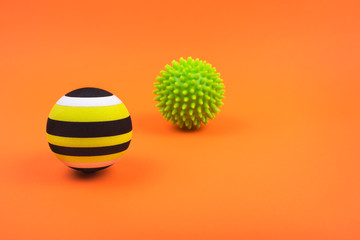 Set of two green myofascial release and massage balls for trigger points over burnt orange color background.