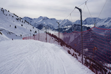 Fototapeta premium ski slope with red net protection in the Alps, France with a wide panorma