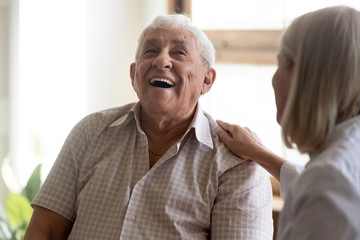 Excited older man laughing, having fun with caregiver close up, happy elderly patient satisfied by...