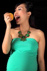 woman pregnancy eating apple with black background