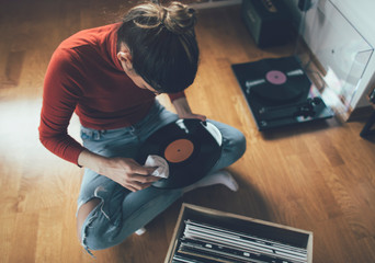 Young audiophile sitting on floor and cleaning dust form her vinyl record collection