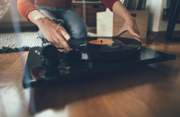 Playing vinyl record. Cropped shot of woman sitting on floor and playing music on turntable