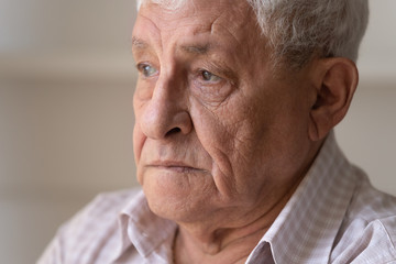 Head shot close up unhappy lonely thoughtful older man looking to away in distance, upset mature grandfather lost in thoughts or memories, thinking about problem, elderly and nostalgia and loneliness