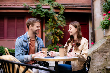 Selective focus of couple with disposable cups of coffee in cafe in city