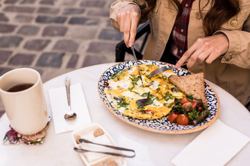Cropped view of woman eating omelette in cafe
