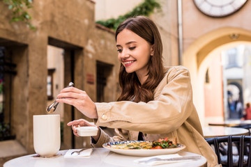 Selective focus of woman putting Sugar cube in cup of tea in cafe in city