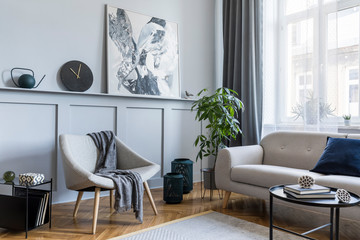 Stylish scandinavian home interior of living room with design gray sofa, armchair, marble stool,...